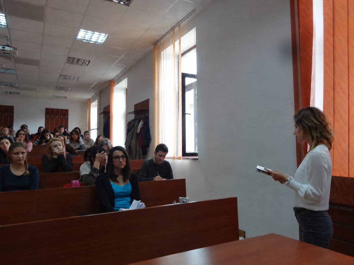Dr. Cezara Humă predând limba germană într-un amfiteatru universitar, în fața unei grupe de studenți